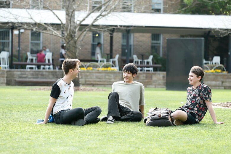京都外国語大学 芝生の上で談笑する学生